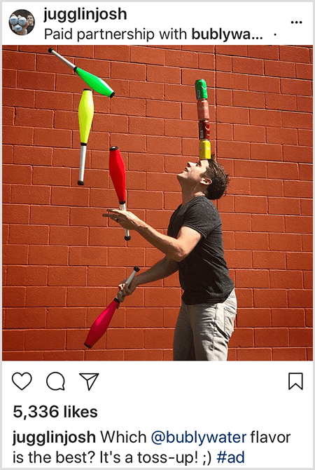 Josh Horton žongleerib nelja pähe laotud Bubly veekannu värvidega sobivate klubidega. Taust on punastest tellistest sein. Foto on Josh Bubly veele loodud reklaam, mis postitati oma Instagrami voogu kirjeldusega, milline mullivee maitse on parim? See on Toss Up!